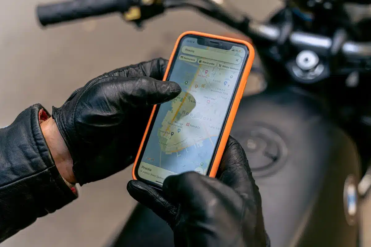 anonymous hand holding a smartphone showing a map pin surrounded by café icons, out-of-focus street scene behind
