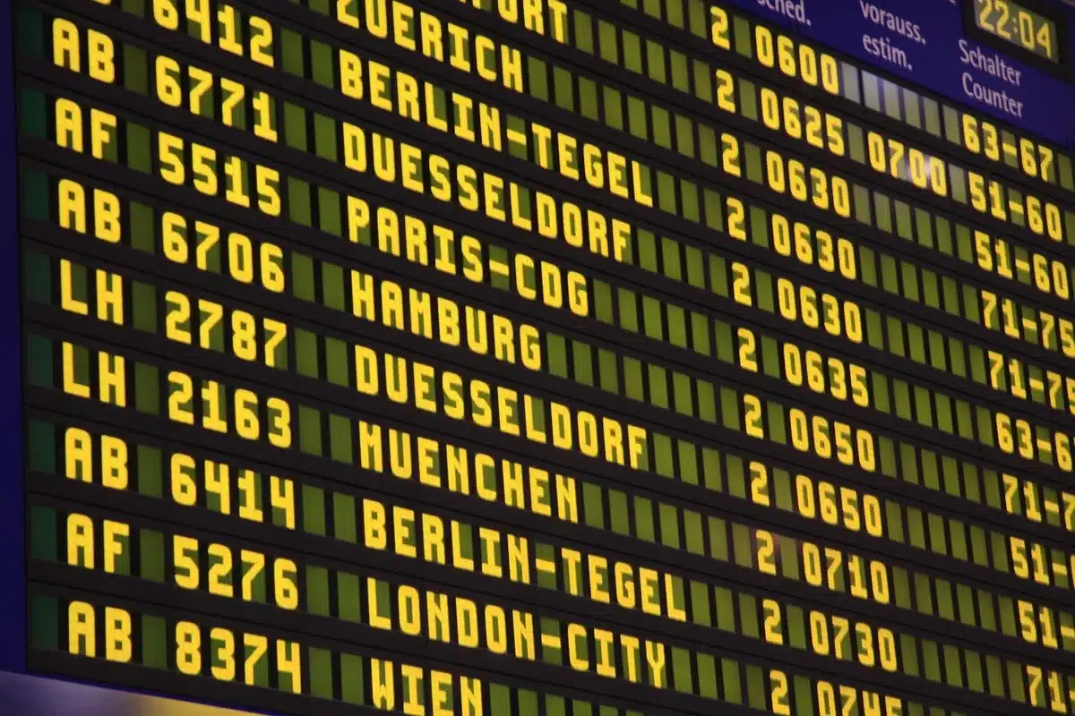 A close view of an airline advisory board in a departure hall showing generic alert icons and blank message panels, empty seats nearby—an institutional travel-safety scene