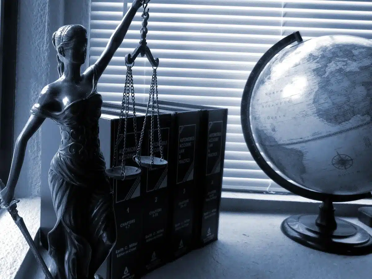 A row of anonymous legal books on a shelf with a single pair of reading glasses resting on top, light through a courthouse window