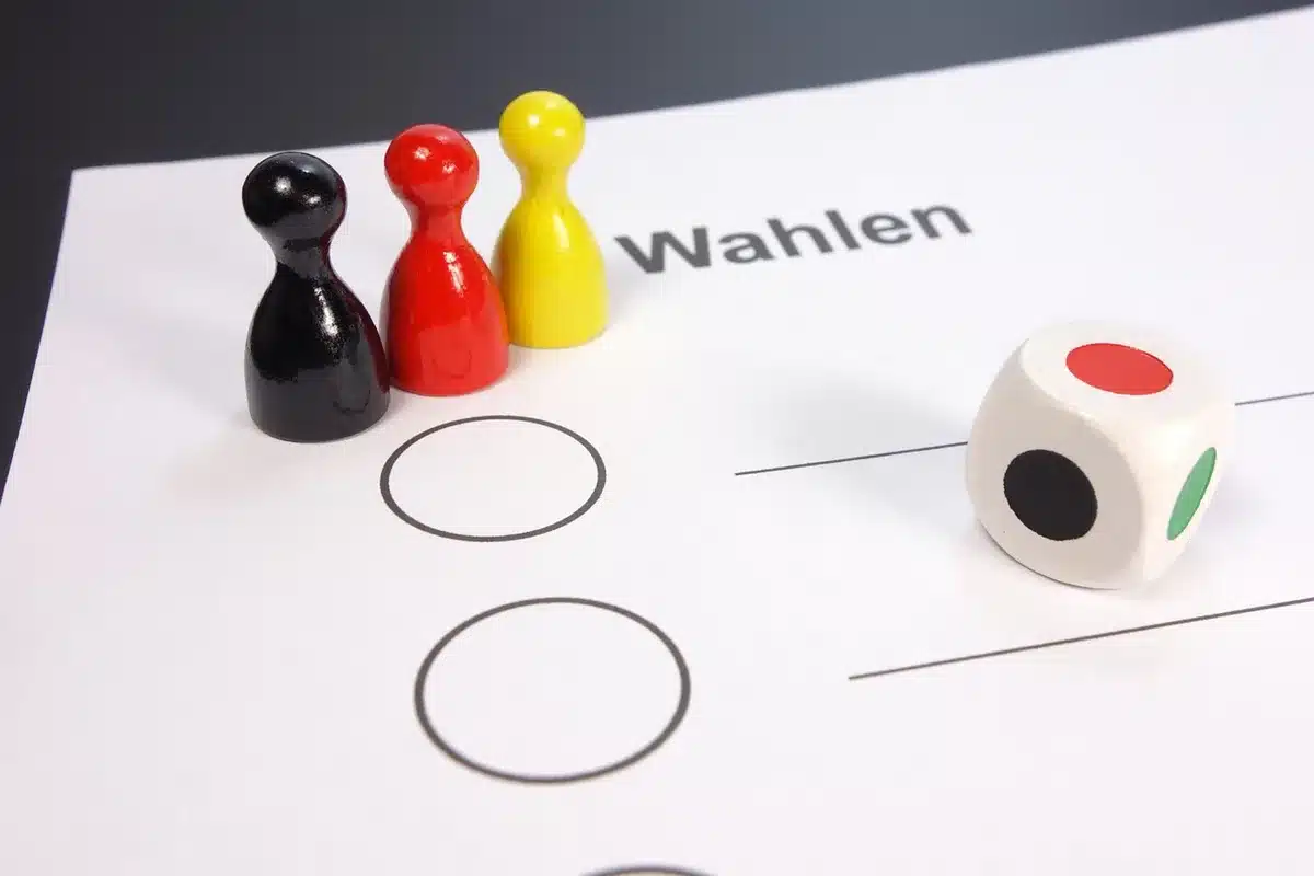 Anonymous hands holding a sample ballot and a photo ID at a table with a pen and a clipboard, a blurred sign in the background, no readable text or logos