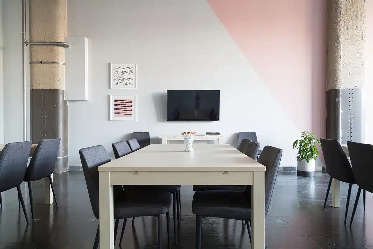 An empty corporate meeting room with a long table, two anonymous chairs pushed back, and a folded agenda on the table suggesting a major vote coming; quiet, anticipatory scene