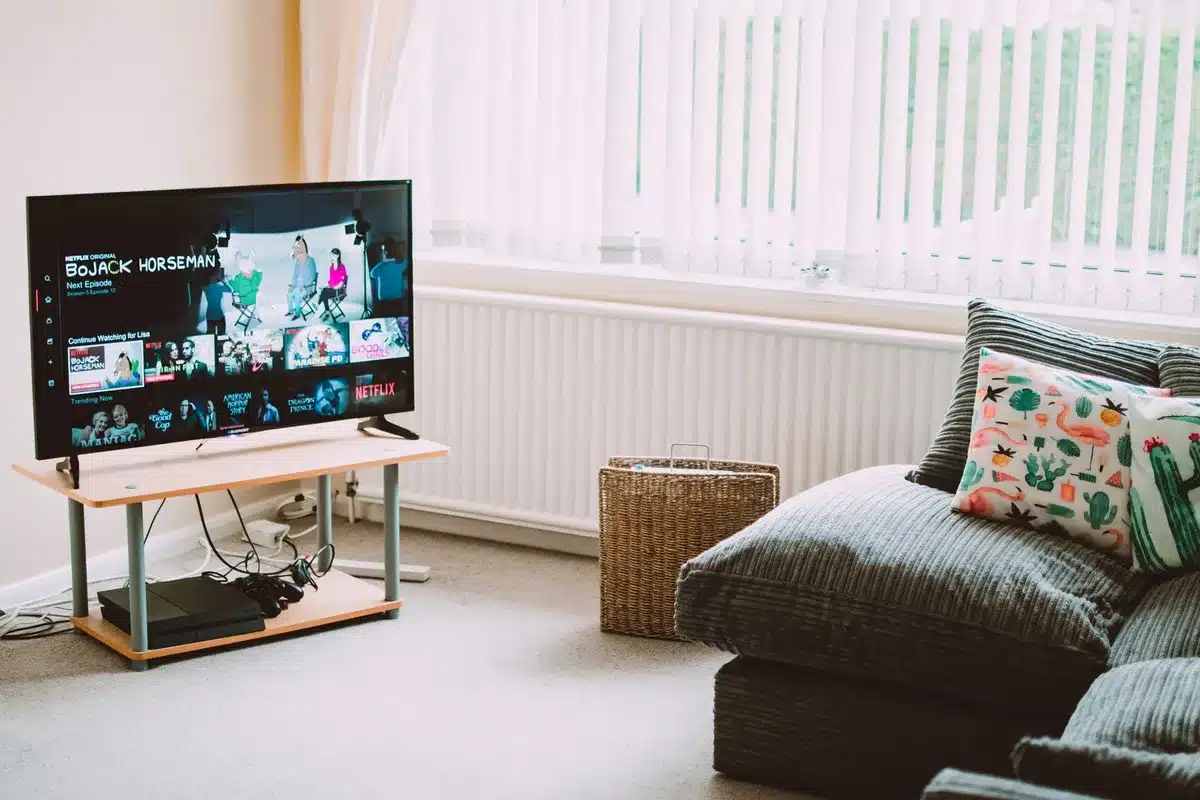 An anonymous living room with a large TV showing a blurred racing feed; an unbranded streaming interface on screen and a remote on a coffee table