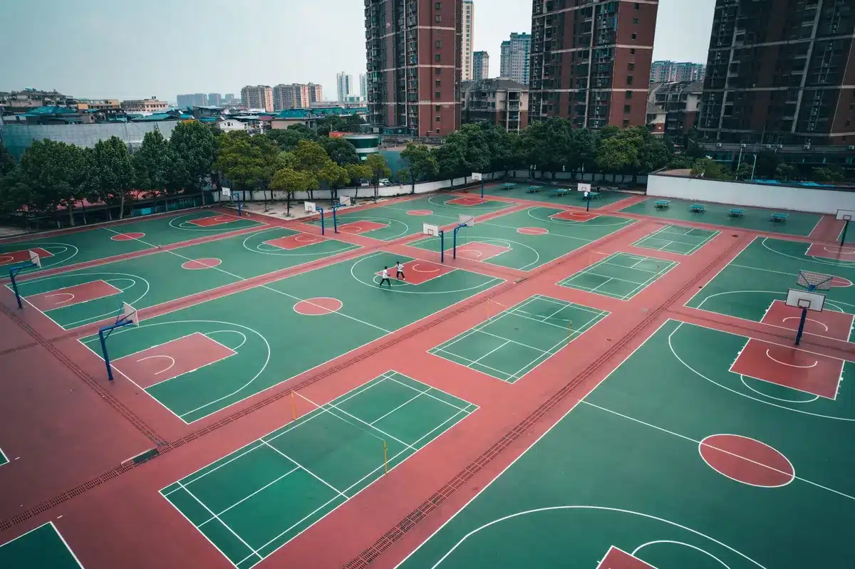 An empty basketball court at dusk with a single spotlight on the center circle, an unbranded leather ball resting on the free-throw line, the stands dark and vacant