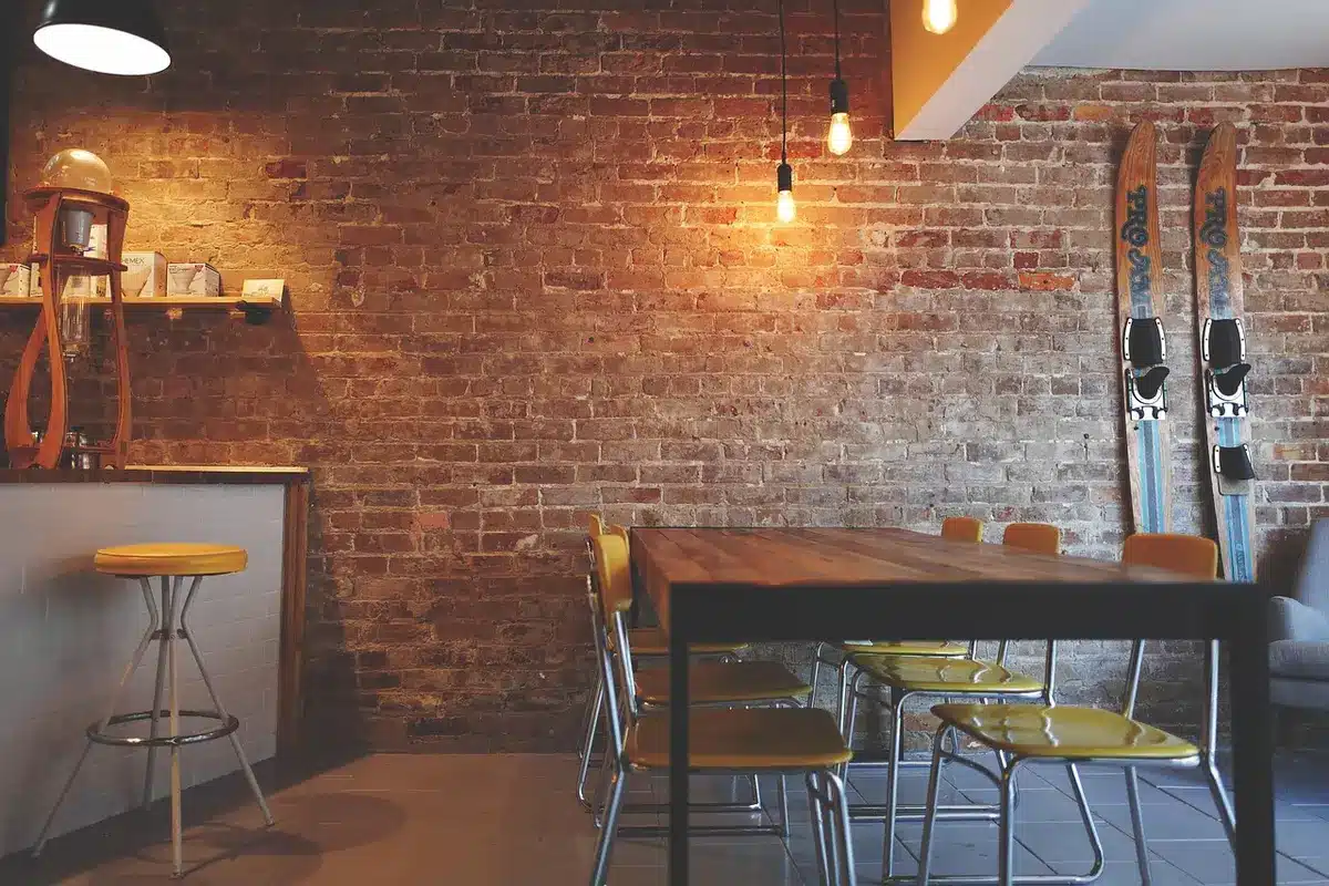 A dimly lit campaign office with an empty volunteer table scattered with unbranded yard signs and coffee cups, a laptop open to social media feeds, a single chair pulled back as if recently vacated