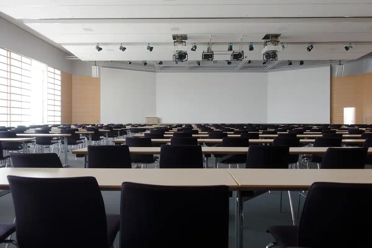 An anonymous empty diplomatic meeting room with a single chair at the head of a long table, papers and an unbranded folder left on the table suggesting a recent departure