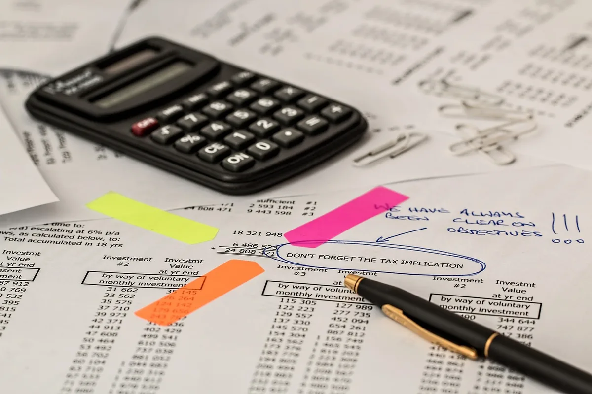 close-up of an analyst's desk with a laptop showing a blurred financial chart, a notepad with scribbled figures, and a coffee cup