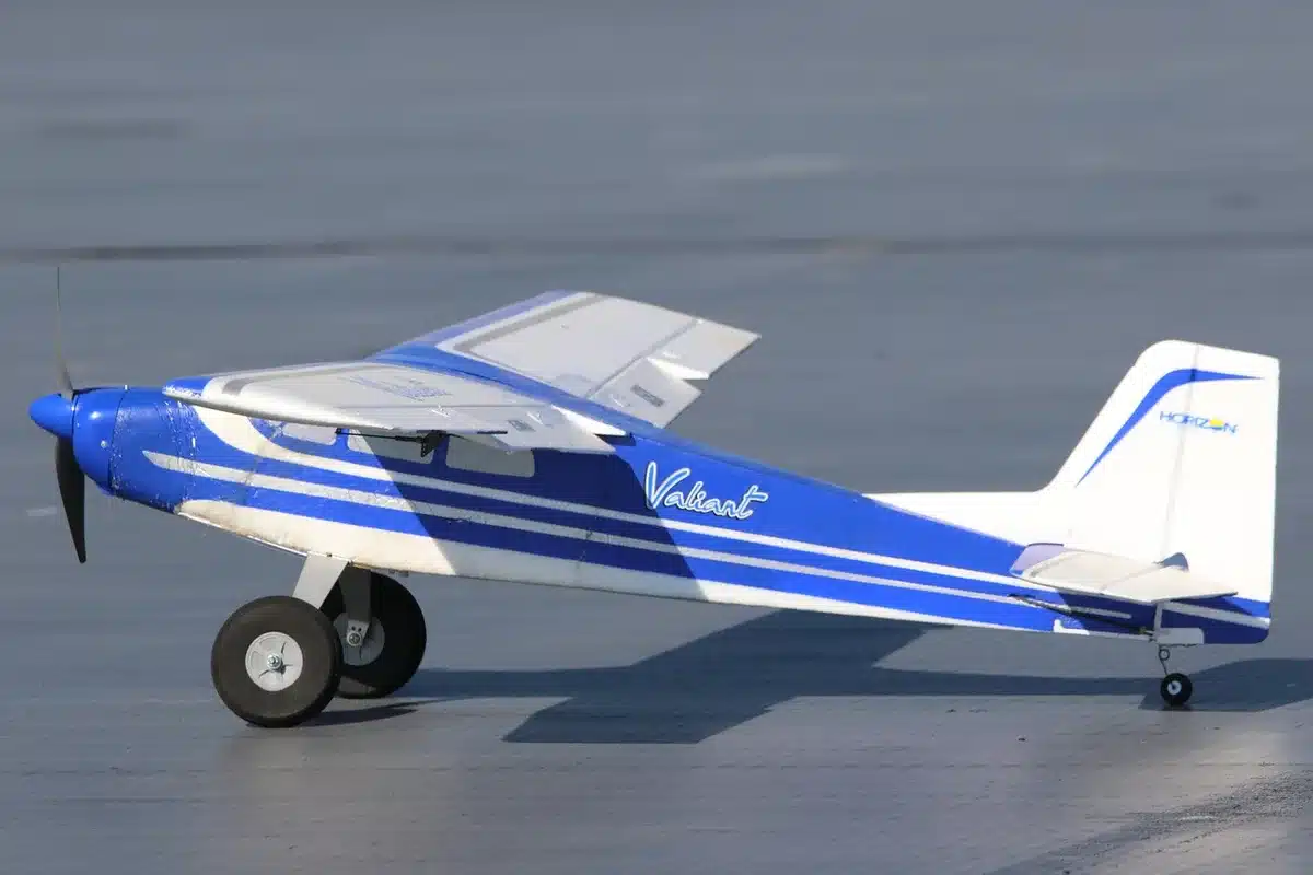 A single empty conference table with a small unbranded model airplane and a lone folder labelled generically, sunlight across the wood surface, no people visible