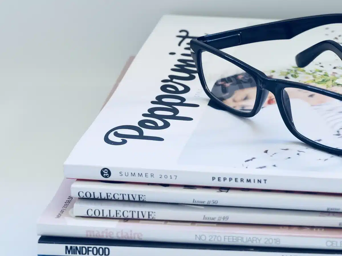 a dimly lit vintage magazine rack with anonymous, unbranded cover edges visible, a mid-century typeface peeking from the top issue