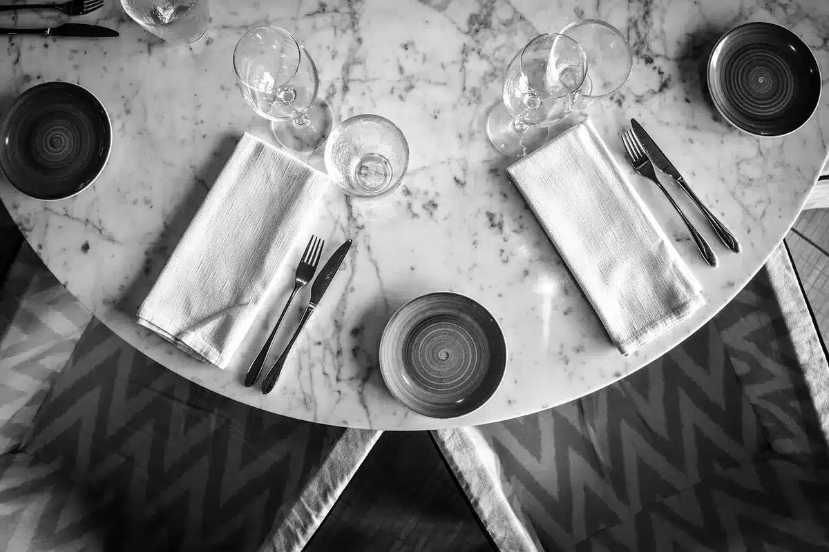 An empty presidential dining table set for a formal dinner, candles low and chairs pushed in, with an unused place setting visible in foreground