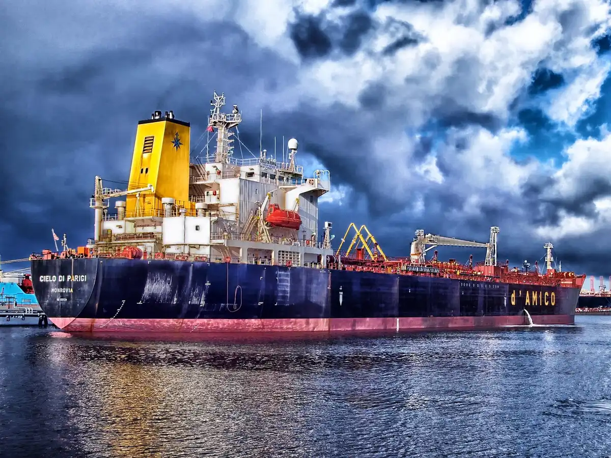 A generic oil tanker at sea at dusk, silhouette against a low sun, no markings visible