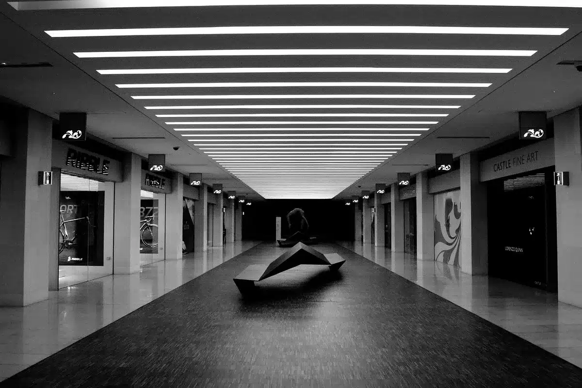 Empty school corridor with scattered backpacks and a single stopped pair of children’s shoes near a classroom door, fluorescent lights overhead
