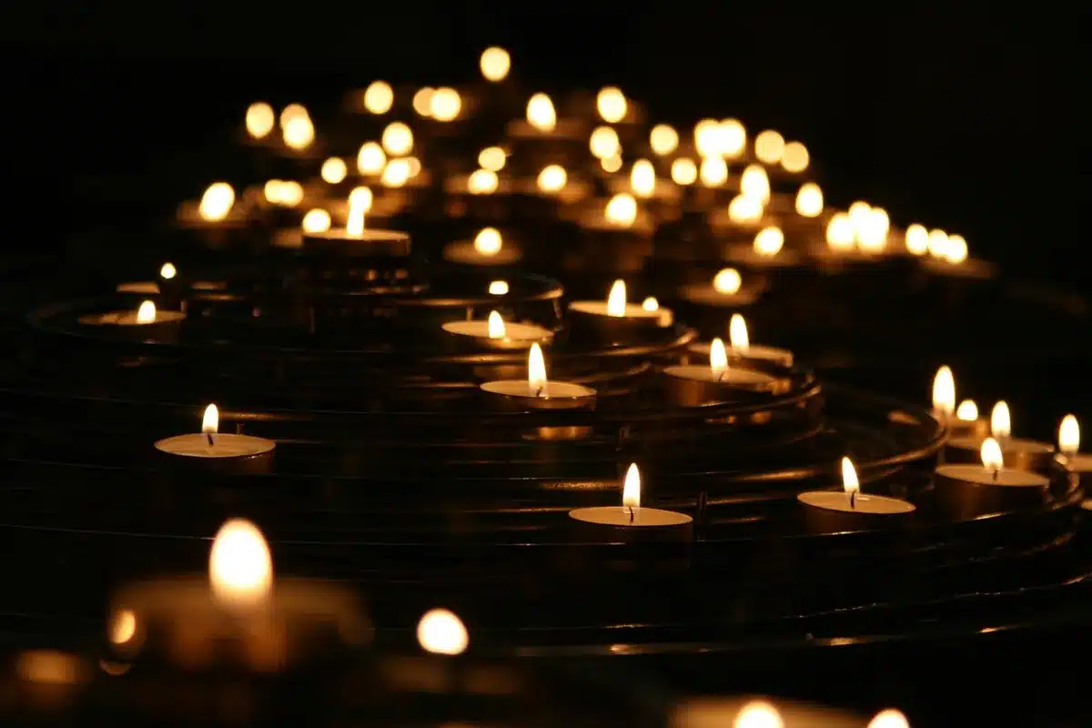 Anonymous small-group of people holding candles outside a city hall at dusk, faces obscured and blurred, memorial mood